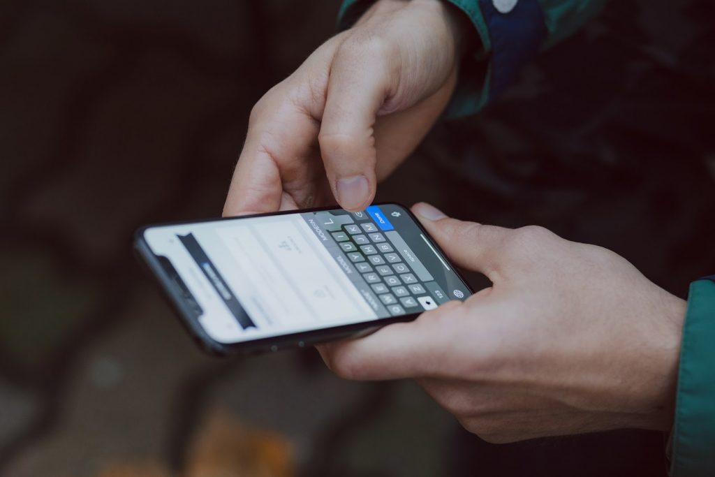 A man holding a smartphone and typing on it - AlikeAudience