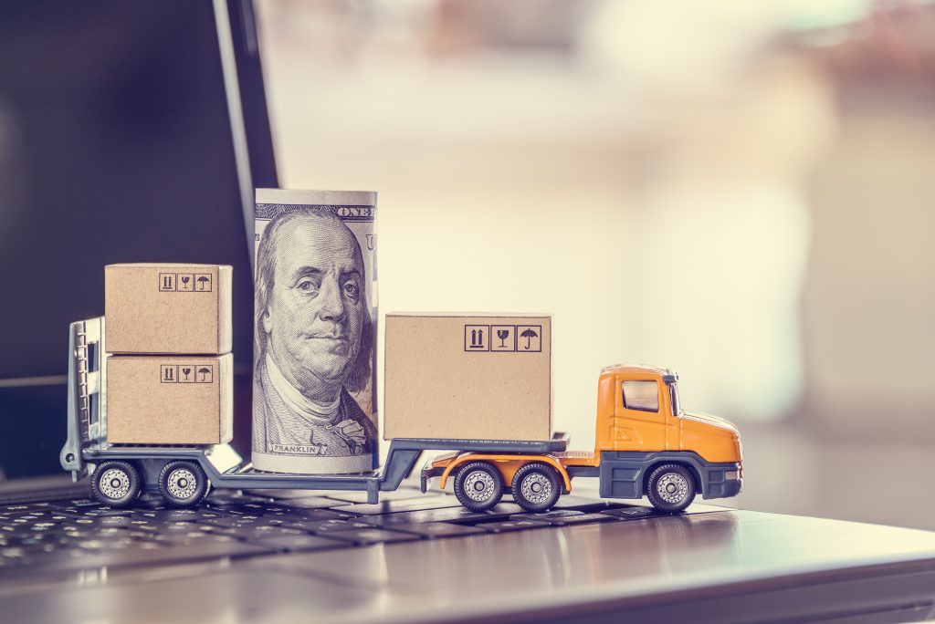 A trailer truck with USD 100 dollar bill and boxes depicts increasing cost of advertising on retail media networks along with delivery service from internet retail